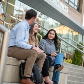 College students sitting in front of a school building