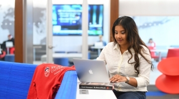 Female student sitting at table working on computer