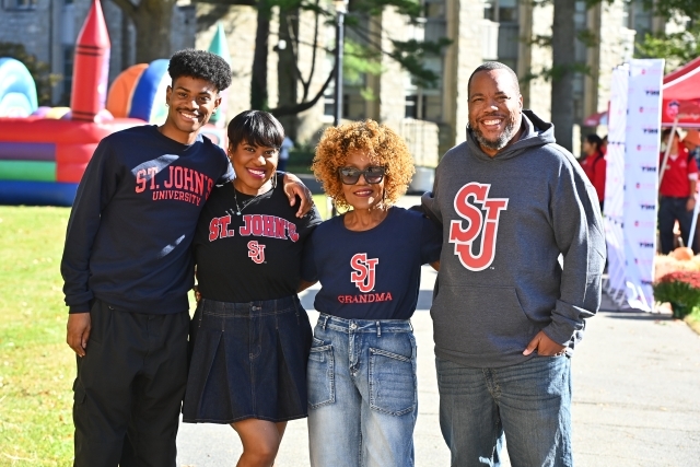 Four people wearing St. John's sweatshirts on the Great Lawn.