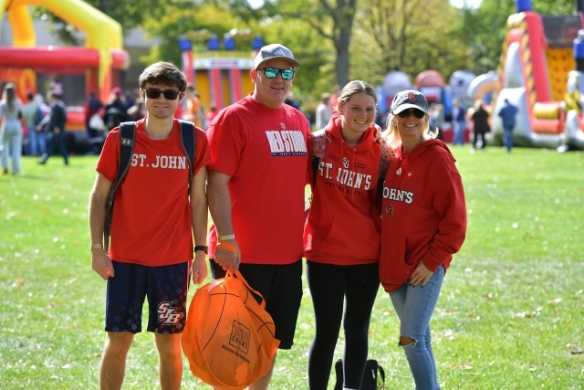 Four people wearing red St. John's t-shirts on the Great Lawn.