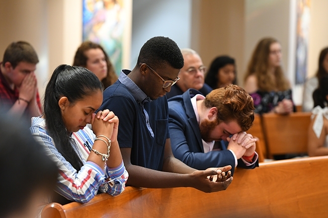 Students praying in pews during Mass