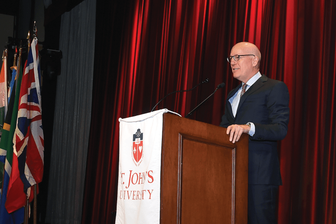 Insurance leader of the year standing at podium with St. John's University banner hanging from it