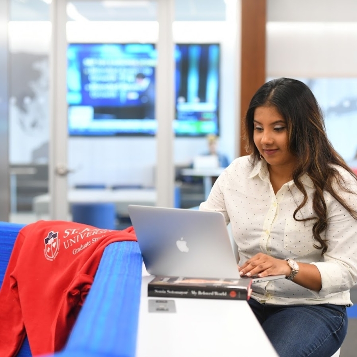 Female student sitting at table working on computer