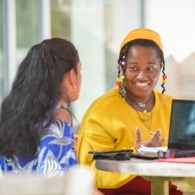 Two female St. John's students talking outside at table