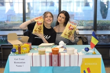 Two female students at a table with sign that says "Get Your Romanian Name"