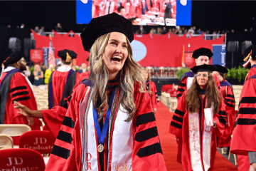 A graduate laughs as she walks off the stage after being hooded.