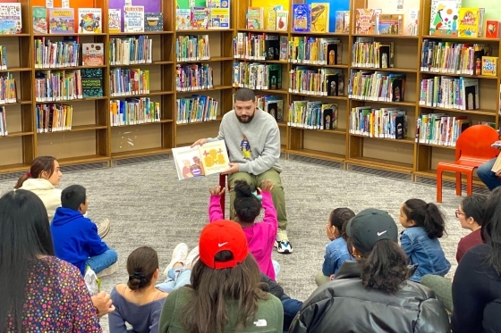 Jorge Santos ’10CPS, ’12G, ’18GEd reading his book to a group of young students