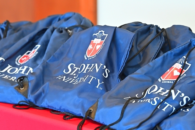 Navy blue St. John's University drawstring backpacks in a stack on a table