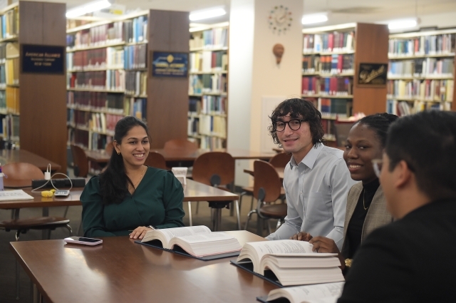 Graduate students networking in a library setting, collaborating on projects and discussing career opportunities.