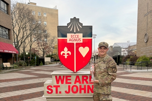 Cadet Mikolaj poses by the We Are St. John's crest statue