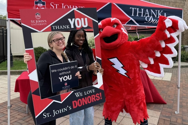 Students with Johnny Thunderbird holding signs thanking donors for their donations