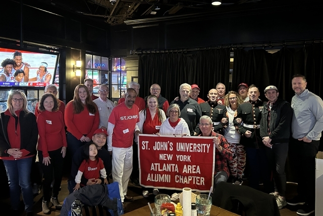 2024-25 Basketball Season Pregame Reception attendees holding banner