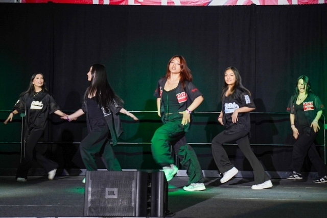 Five St. John's students dressed in black jerseys dancing on stage