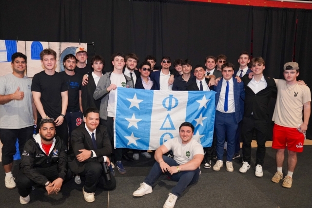 St. John's Fraternity members posing for photo holding a flag
