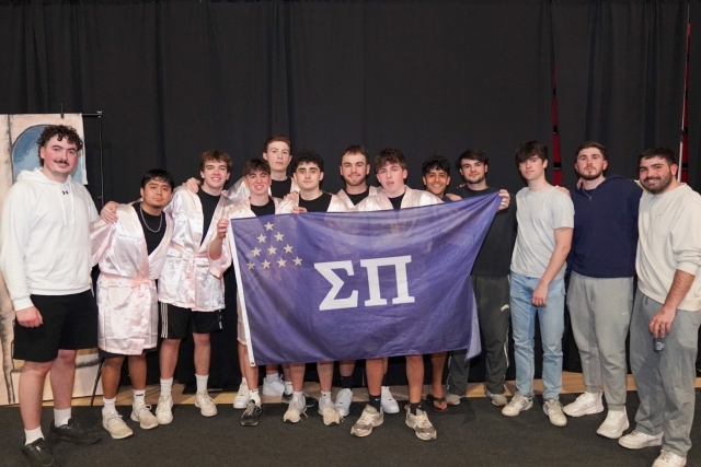 St. John's Fraternity members posing for photo holding a flag