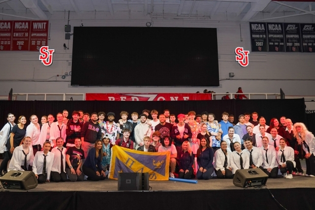 St. John's students on stage holding a flag