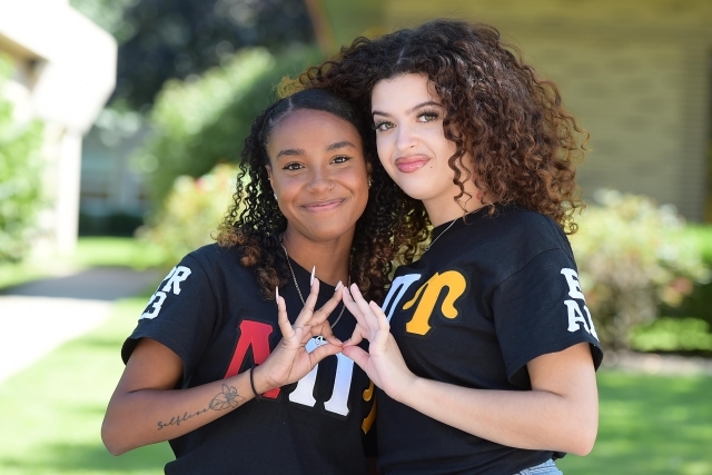 St. John's students making the lpiu hand gesture while hugging
