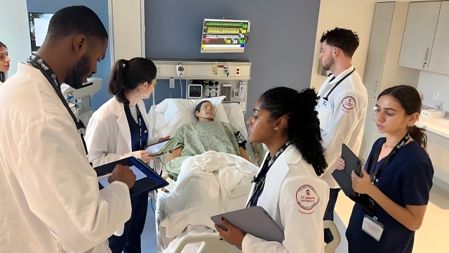 Students in lab coats working in patient simulation lab