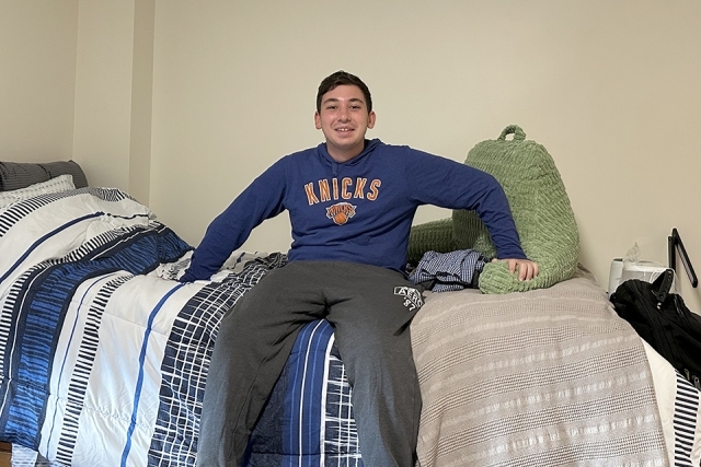 Student sitting on his bed in residence hall during first year move in.