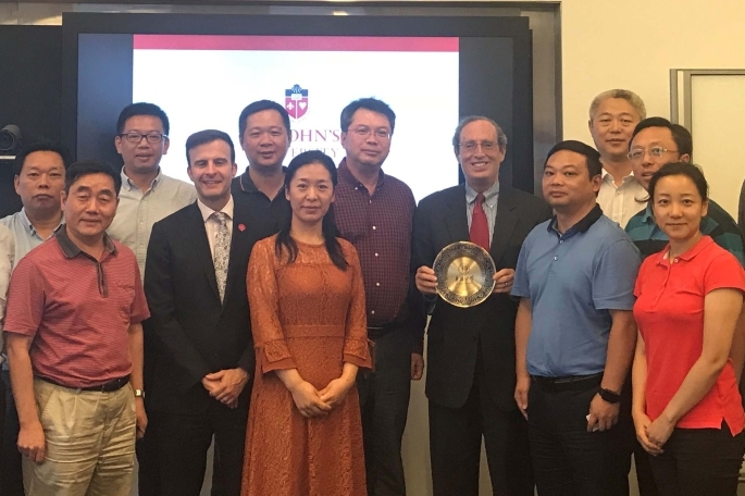 Group of students and professors standing infront of screen posing for photo
