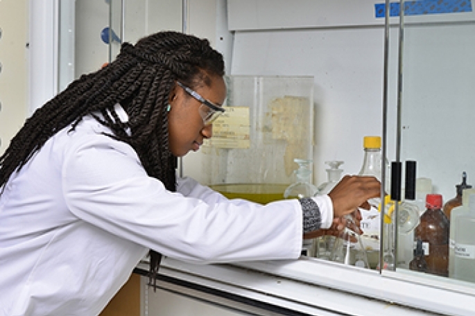 St. John’s student pours liquid into a triangular beaker while conducting health science research.