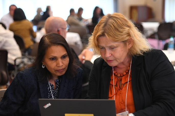 Two female faculty members looking at laptop screen