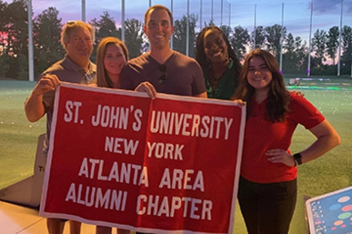 Atlanta Alumni posing with St. John's banner at Topgolf